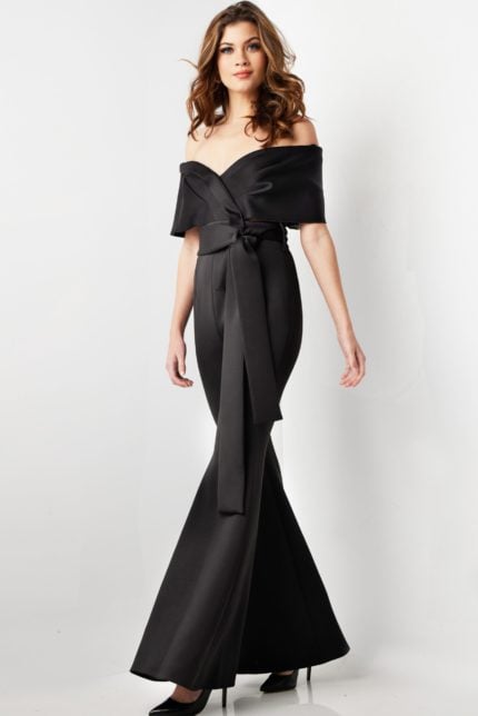 Model wearing Jovani 09726 black off-the-shoulder jumpsuit, angled front view