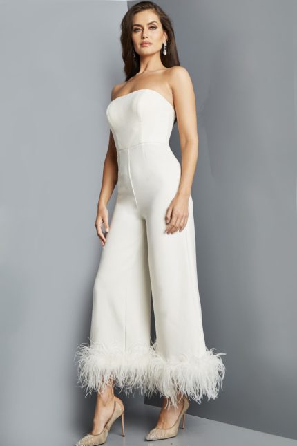 Model wearing Jovani 22590 ivory strapless jumpsuit with feathered hem, angled front view.