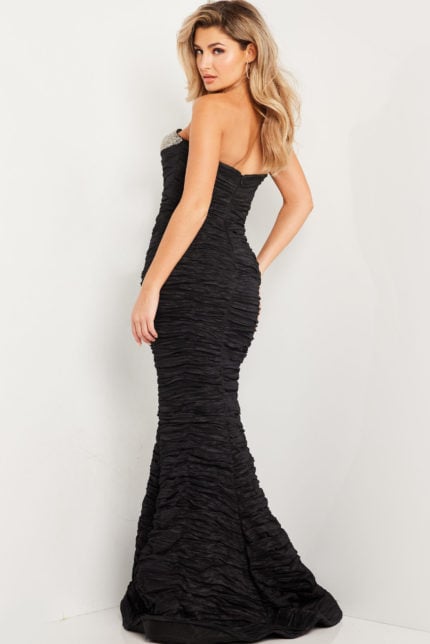 Model wearing Jovani 23546 black mermaid gown, back view showing ruched texture.