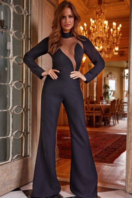 Model wearing Jovani 24297 front view showcasing black jumpsuit with sheer neckline and long sleeves.