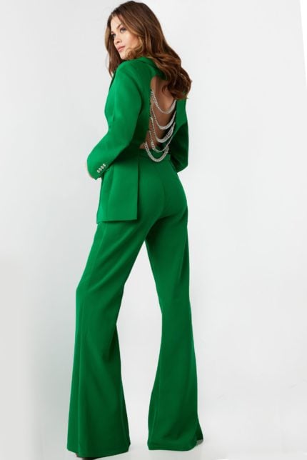 Model wearing Jovani 26144 green pantsuit with open back and chain detailing.