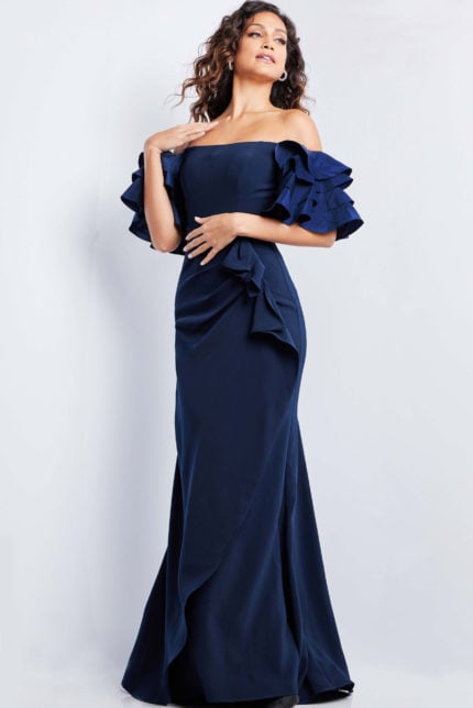 Model wearing Jovani 37674 navy gown front view with off-the-shoulder ruffles and mermaid silhouette.