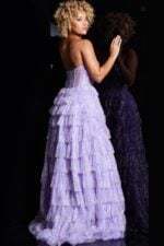 Back view of model wearing Jovani 38165 lilac dress with layered ruffles and strapless design.