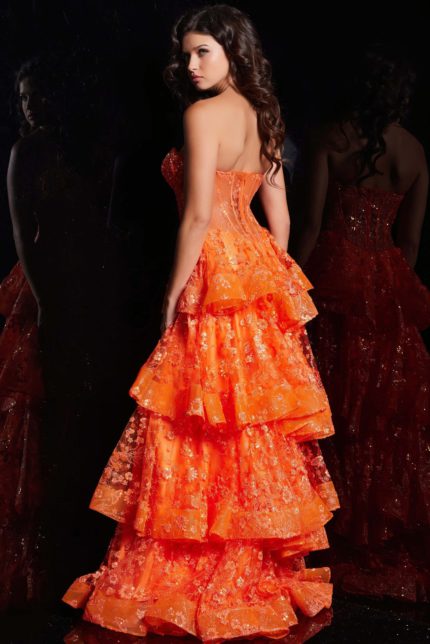 Model wearing Jovani 38528 orange dress showcasing the back with tiered ruffles