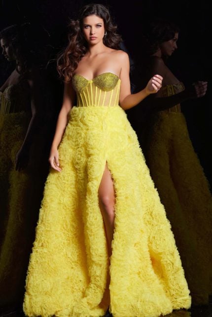 Model wearing Jovani 38674 yellow gown with floral appliqué and high slit.