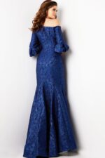 Model showing back view of Jovani 38791 navy mermaid gown with off-the-shoulder design.