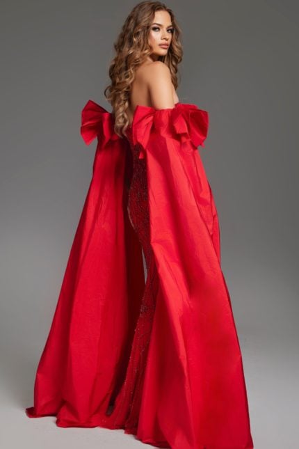 Model wearing Jovani 39377 back view showcasing flowing red cape and fitted gown silhouette.