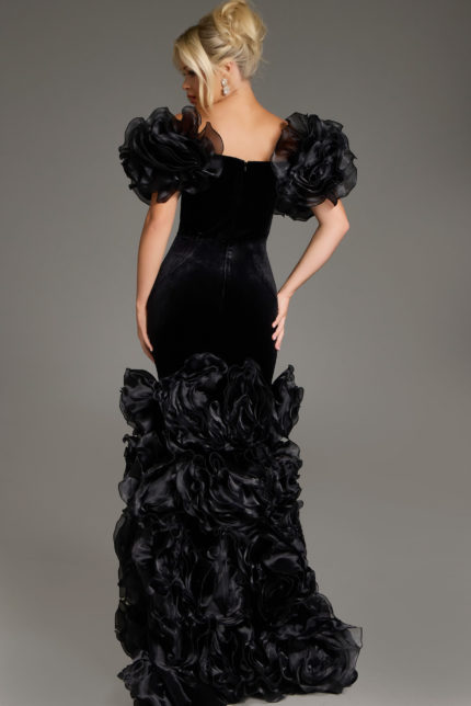 Back view of model in Jovani 40843 black velvet gown showcasing a fitted bodice and dramatic ruffles.