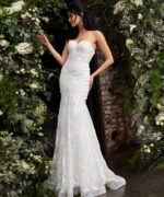 Model wearing JB02836 elegant white gown with lace appliqués, front view, surrounded by flowers