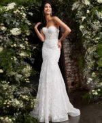 Model wearing JB02836 elegant white gown with lace appliqués, front view, surrounded by flowers