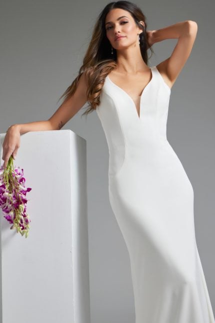 Model wearing Jovani JB42222 ivory dress with V-neckline leaning on prop.