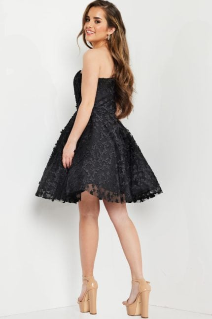 model wearing K23516 black dress in a back view, displaying the flow of the fabric.