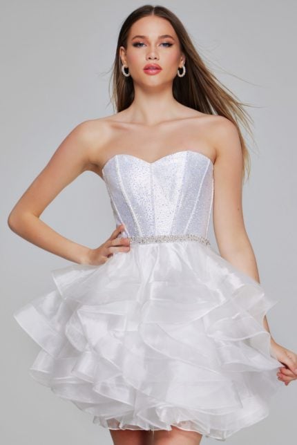 Model in Jovani K39311 off-white mini dress with glittering bodice and ruffled skirt.