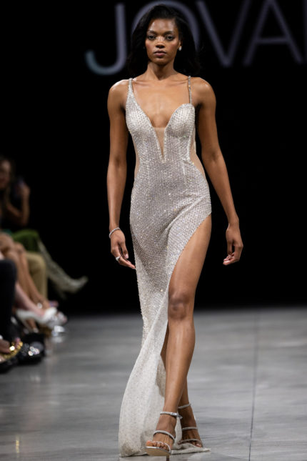 Model wearing Jovani S23022 beige gown with plunging neckline and high slit in front view