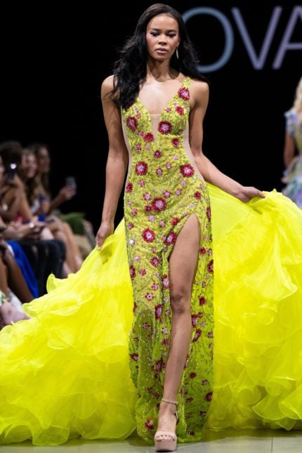 Model wearing Jovani S24070 with a vibrant multi-color design, plunging neckline, and high slit.