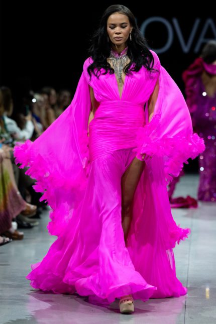 model wearing S36352 vibrant pink gown with plunging neckline and cape sleeves