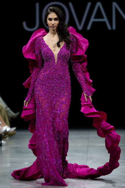 Model wearing Jovani S36413 fuchsia gown with beadwork and ruffled sleeves.