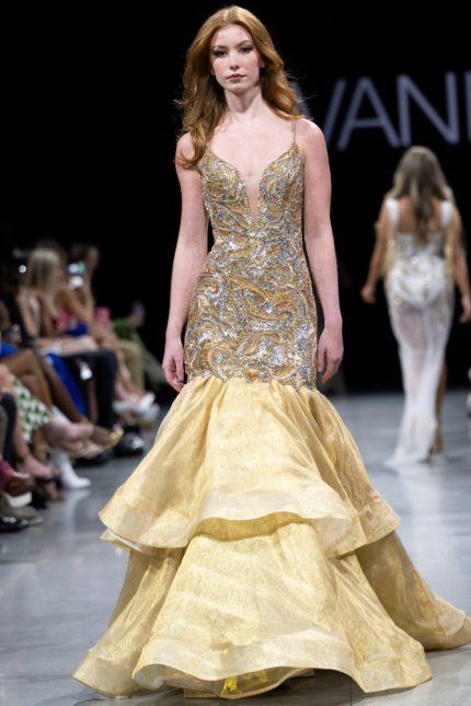 Model wearing Jovani S38449 gold mermaid gown with a plunging V-neckline and layered skirt