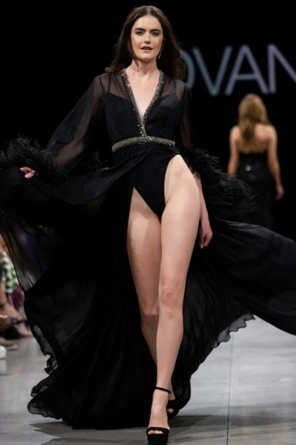 Model wearing S39276 black gown with plunging V-neckline and high slit.