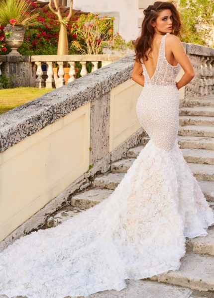 Model wearing Jovani JB07233 white dress with V-back and floral applique train, back view.